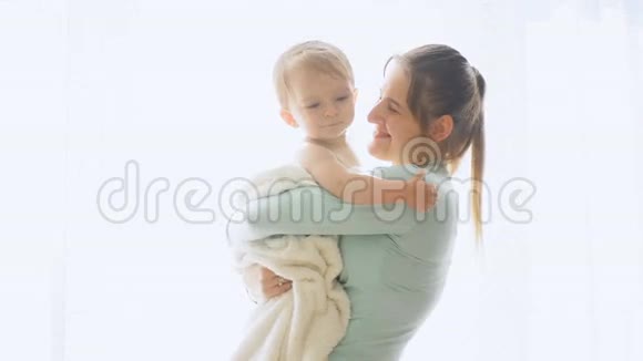母亲在大窗户上抱着婴儿拥抱婴儿的慢镜头视频的预览图