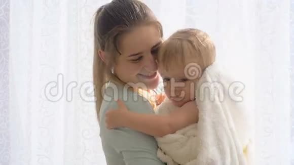 美丽有爱心的母亲把她的小儿子抱在毯子上视频的预览图