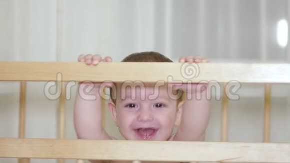 婴儿床上一个迷人的孩子笑着拍手同时试图让她的母亲笑4k视频的预览图