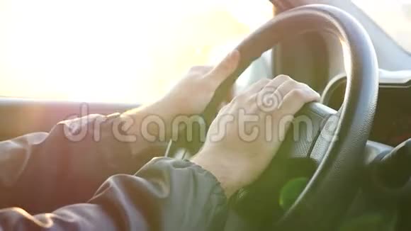 双手放在方向盘上日落时驾驶汽车树后闪烁着光芒慢动作视频的预览图