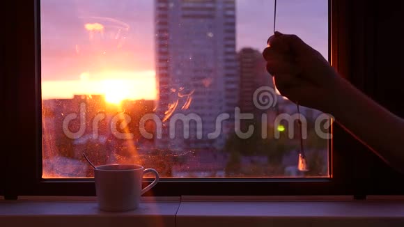 傍晚夕阳西下关上窗户上的百叶窗窗台上放着一杯带蒸汽的粗咖啡视频的预览图