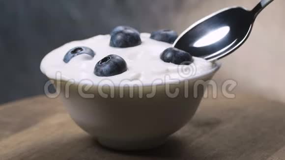 用勺子吃蓝莓和奶油或酸奶水果背景视频的预览图