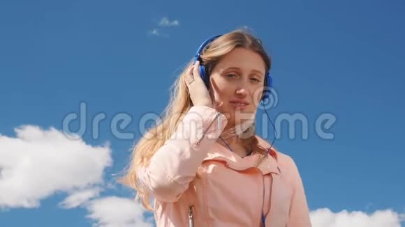 年轻女人和牛仔裤在户外戴着耳机听音乐视频的预览图