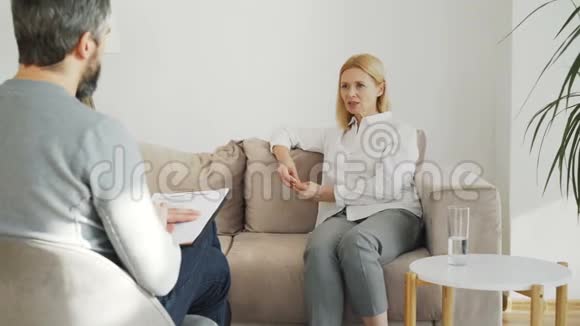 患有抑郁症的成年压力妇女在室内心理治疗办公室与男性专业精神分析人员交谈视频的预览图