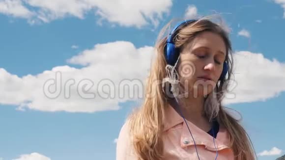 在户外用耳机听音乐的年轻女子视频的预览图