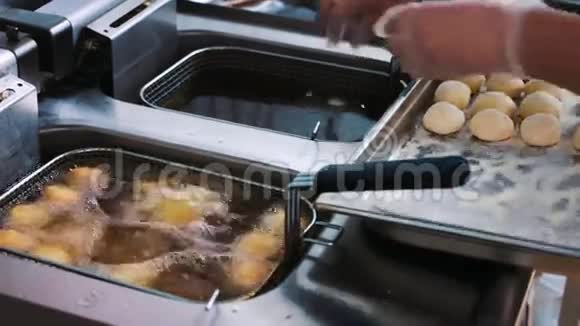 厨师用热油把面团扔进深油炸锅里做饭油煎的甜甜圈厨师的手视频的预览图