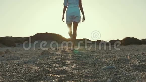 穿着白色连衣裙的女孩从相机走到日落沙漠慢动作视频的预览图