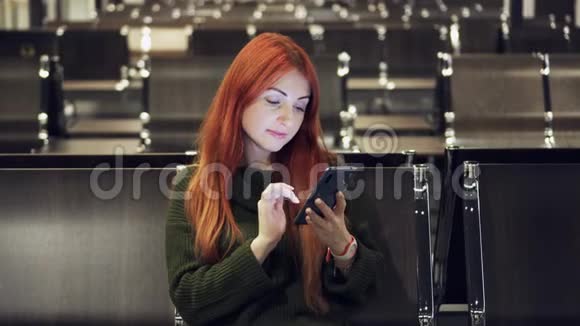 年轻女性在机场候机楼使用电话视频的预览图