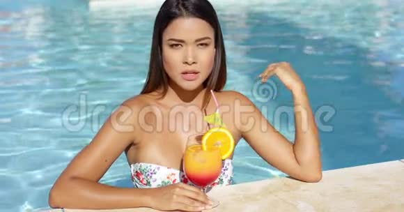 一位严肃的年轻女士喝着橙色朗姆酒鸡尾酒视频的预览图
