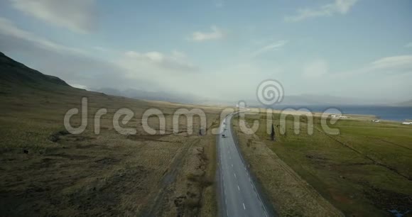 鸟瞰海洋和山谷汽车在农村公路上行驶周围是田野视频的预览图