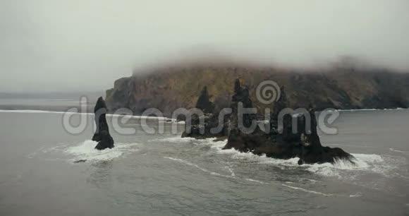 科普特在冰岛的海上翻着巨魔的脚趾悬崖美丽的黑色火山海滩和雾中的山视频的预览图