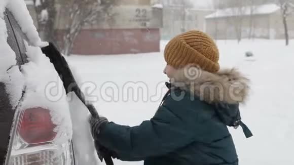 冬天早晨户外的小男孩在打扫一辆雪车视频的预览图