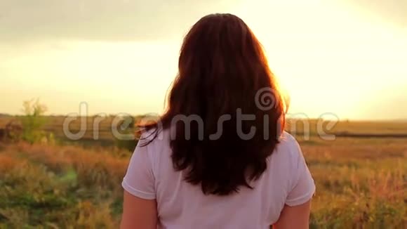 日落时分在森林附近的田野里散步的女孩视频的预览图