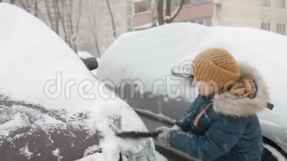 冬天早晨户外的小男孩在打扫一辆雪车视频的预览图
