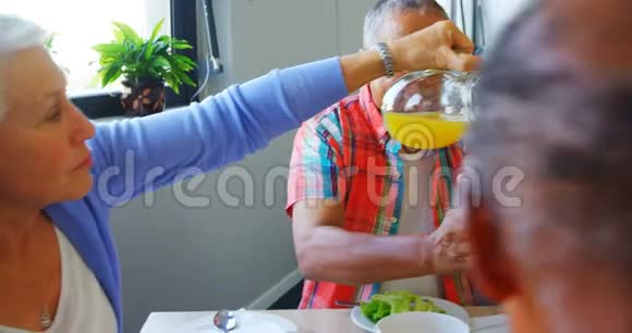 一位老妇人把果汁倒进她的朋友杯子里视频的预览图