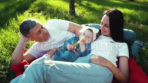 夏园绿草毯上抱着女婴的爱心家庭视频的预览图