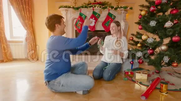 幸福的年轻夫妇装饰圣诞树互相扔硬币视频的预览图