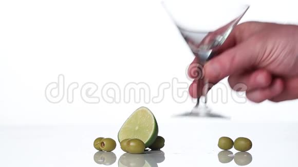 马丁尼威茅斯或利口酒倒在玻璃杯里桌子上的石灰和橄榄视频的预览图