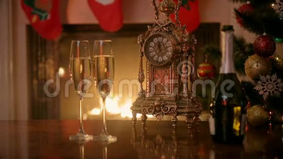 两杯香槟和复古钟在燃烧的壁炉前的房子庆祝圣诞节的概念视频的预览图