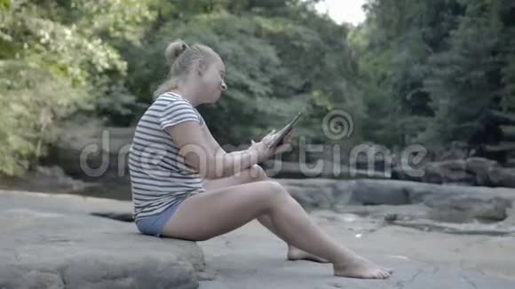 坐在山溪边岩石上的女孩视频的预览图