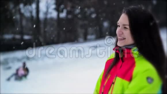 女子穿着五颜六色的滑雪服的特写肖像雪花缓缓飘落留着长发的可爱少女视频的预览图