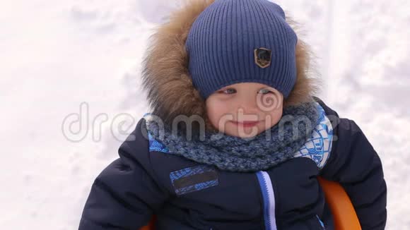 一个微笑的男孩在冬天雪橇的肖像视频的预览图