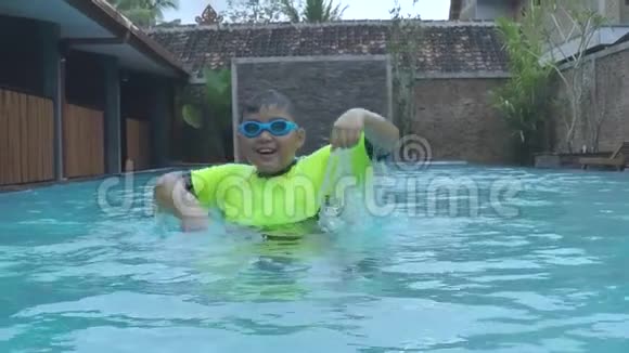 小男孩在游泳池里玩水的慢动作视频的预览图