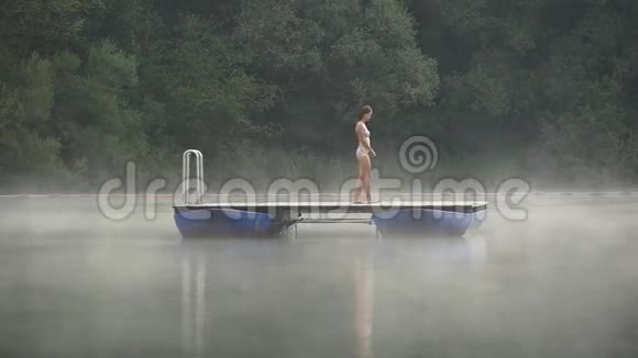 女人在清晨的雾霭中的湖上漫步视频的预览图