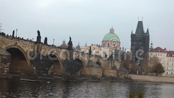 位于布拉格的老塔和大教堂绿色穹顶背景上的查尔斯桥侧视游客视频的预览图