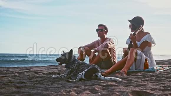 年轻夫妇在海滩上玩得很开心岛上的周末年轻夫妇在海滩上用吉他唱歌他们的滑稽视频的预览图