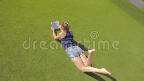 从顶部看公园里躺在草地上看书的年轻学生女孩视频的预览图