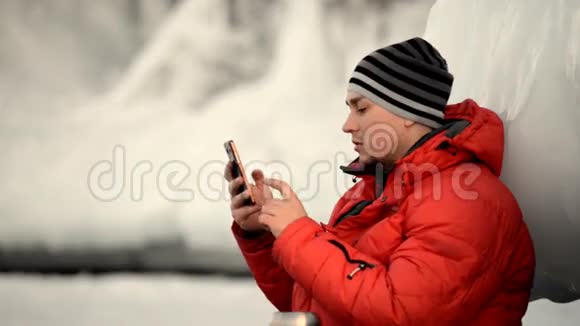 那个人正在冰岩边使用智能手机视频的预览图