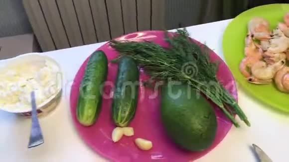 酥皮牛油果黄瓜和厨房用具躺在桌子表面煮熟的虾躺在盘子里视频的预览图