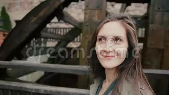 一位美丽的年轻女子站在一个古老的乡村水磨厂附近笑得很开心视频的预览图