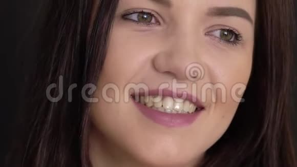 年轻的黑发女人微笑着在黑色背景下交谈视频的预览图
