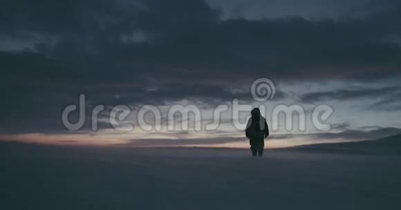 一位穿着传统驯鹿皮大衣的北极旅行者在美丽的日落下经历暴风雪视频的预览图