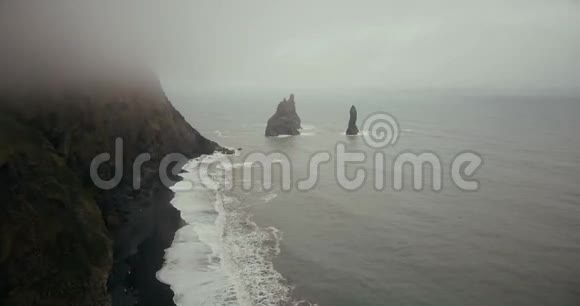 科普特飞越美丽的黑色火山海滩和巨魔脚趾悬崖在冰岛海雾浪的景观视频的预览图