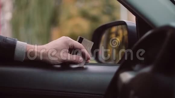 近距离观看男子手中拿着信用卡坐在车里等待付款视频的预览图