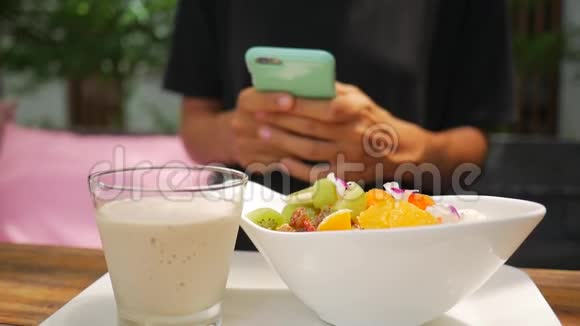 在她健康的素食早餐期间女性用手机扭动用智能手机关闭一只年轻女孩的手高清高清视频的预览图