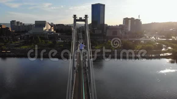 一个人走在一根绳子上绳子在桥的支架之间在高空视频的预览图