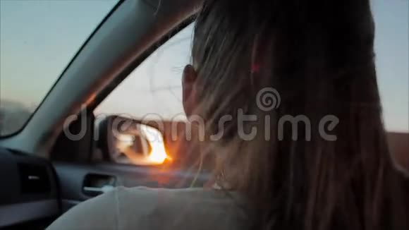 风吹过女孩的剪影和头发在车里少女在车里听音乐日落视频的预览图