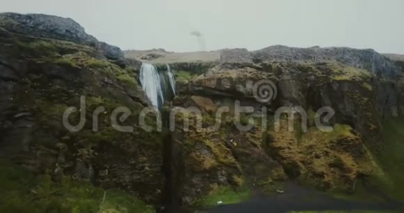 用河流俯瞰美丽的山谷飞越冰岛山脉之间的Gljufrabui瀑布的科普特视频的预览图