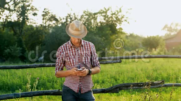 带帽子的年轻人使用智能手机农村视频的预览图