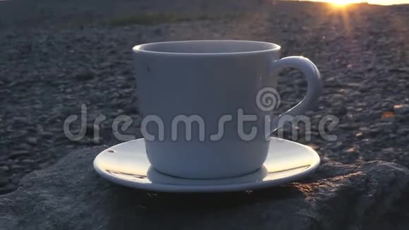 在夕阳的余晖和水上的眩光中加入热茶或咖啡的吸烟杯1920x1080高清视频的预览图