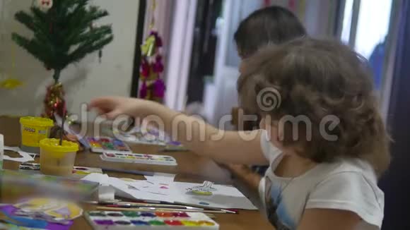 女孩们用颜料在桌子上画房子孩子们在室内画画视频的预览图