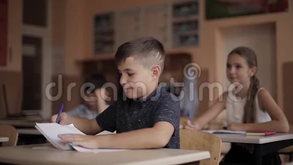 男孩和女孩坐在桌子上写着一篇文章视频的预览图