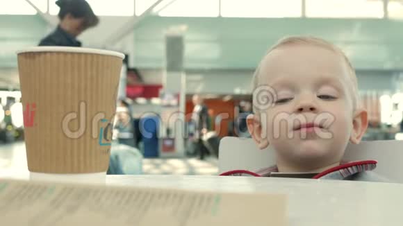 妈妈给她一杯茶去机场这个男孩在咖啡馆里喝热饮料视频的预览图