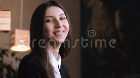 年轻女子喝着卡布奇诺或带牛奶的茶对着镜头微笑视频的预览图
