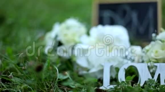 婚礼装饰词爱花和木牌上有字母D和M背景是绿草视频的预览图