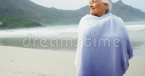 一位老妇人在海滩上用毯子盖着自己视频的预览图
